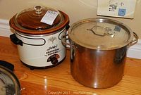 Photo showing the Jubilee brand crock pot with removable glossy brown ceramic liner and glass lid alongside the large stainless steel canning pot with lid.