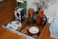Wide shot of all items showing the bean slicer box, floral plate, vase with peacock feathers, mother and child carving, carved figure