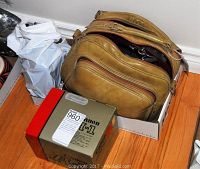 Canon A-1 camera box and brown leather camera case packed together on floor