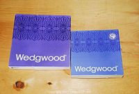 Two original Wedgwood boxes, one larger and one smaller, both purple with white Wedgwood branding and decorative border design.