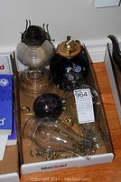 Photo showing two oil lamps and additional chimneys and accessories in cardboard box