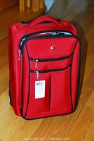 Front view of upright red 20-inch wheeled suitcase with multiple front zippered compartments