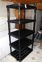 Full view of the black plastic shelving unit showing all five shelves and vertical supports.