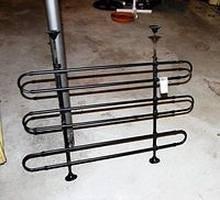 Adjustable black metal pet gate divider for SUV or van, shown standing on the floor with height-adjustable poles fixed with rubber ends.