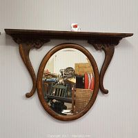 Full view of the antique solid oak wall mirror with attached shelf showing oval mirror and carved shelf supports.