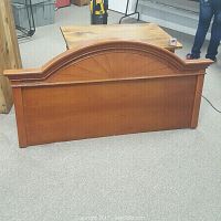 Front view of queen-size wooden headboard showing arched top and decorative carved detailing.