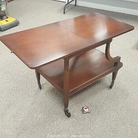 Full view of the bar cart with the top opened up, showing two-tiered surface and caster wheels on four legs