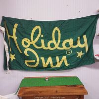 Full front view of green Holiday Inn flag with yellow lettering, showing overall condition and size.