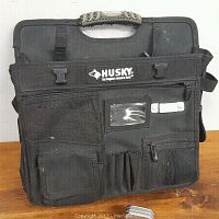 Front view of black Husky tool bag with multiple pockets and Husky branding visible