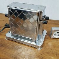 Side view of vintage electric toaster showing diamond pattern metal casing and two black adjustment knobs.