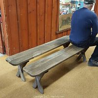 Two long wooden benches placed side by side with one person sitting on one bench.