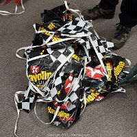 Pile of racing banner flags with Havoline logo and checkered patterns on the floor.