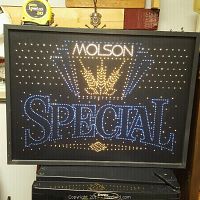 Front view of vintage Molson Special fiber optic beer sign illuminated with blue, white, and yellow lights, showing the brand logo and decorative crown design.