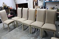 Full view of 6 upholstered dining chairs placed side by side in a room with storage items.
