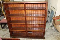 Front view of the wooden bookcase showing multiple shelves and the paneled back design, sides feature handles.