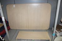 Main large table top piece of light wood color with visible wood grain and rounded corners, shown in a disassembled state.