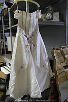 Full front image of ivory wedding dress on hanger showing length and fabric detail