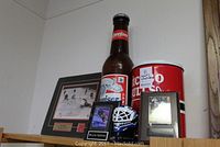 Photo of Chicago Bulls metal canister, unopened 24 oz Budweiser bottle, Wayne Gretzky hockey card and photo plaque, small hockey helmet collectible figurine, and additional framed memorabilia