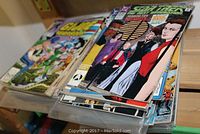 Stack of assorted comic books in protective sleeves showing various character covers and colorful artwork.
