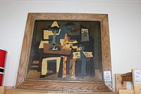Full view of the framed cubist print hanging on a wall, showing abstract geometric figures and the wooden frame.
