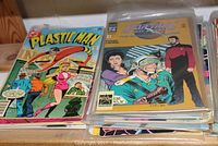 Stack of comic books featuring Plastic Man and Star Trek covers on top.