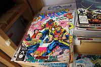 Stack of comic books with X-Men as the visible top comic, colorful cover with multiple characters