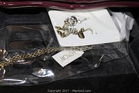 Close-up photo of dangling earrings with gold-tone and pearl-like beads in plastic packaging.