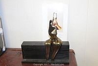 Full front view of the abstract metal sculpture seated on wooden base