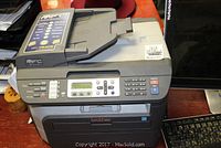 Front and side view of Brother MFC-7840W printer showing control panel, LCD screen, numeric keypad, and paper feeder tray.