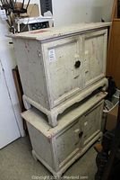 Two stacked distressed white painted Asian style wooden side tables showing overall wear and design features.