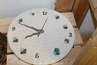 Photo of the beige textured 12-inch round battery operated wall clock with stone and glass hour markers and metal hands