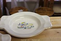 Top view of a Nelsonware child-themed bowl with side handles and colorful illustration of a child with a lamb, gold trim around edges