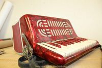 Close-up photo of red accordion showing marbled finish and keyboard with missing key cover