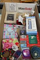 Full lot view showing assorted costume jewelry, a power bank phone charger, trinket boxes, a pen, business card holder, pedometer, and novelty small boxes.