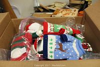 Top view of box containing multiple Christmas themed novelty bottle sweaters and socks in packaging.