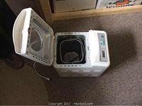 Open bread maker showing interior with bread pan and kneading paddle inside.