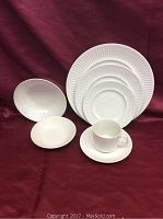 Grouped photo showing white ironstone dinner plates along with bowls and a cup for scale. Plates have ribbed edge detail.