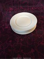 Stack of 8 white plates showing the design and size.