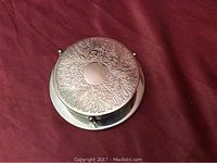 Silver plated coaster stand with six stacked coasters on top showing engraved floral pattern