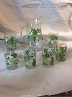 View of the 7 piece juice set showing the pitcher and all six glasses with green apple painted design.