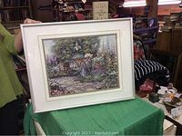 Front view showing framed artwork of flower cart in garden with grey frame and white matting.
