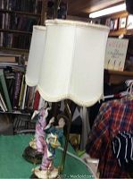 Pair of Asian motif table lamps on green cloth-covered table with surrounding background of clothing and store items.