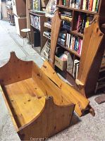 Colonial style pine baby cradle and matching stand disassembled and placed on floor. The cradle is rectangular with tall end boards and visible wood grain.