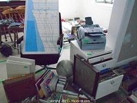 Photo of filing cabinet with open drawers, assorted stationery, art supplies, lunar globe, office chair and fax machine seen in the background.