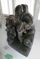 Front and left three-quarter view of the kneeling hunter holding an animal