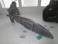 Full frontal view of soapstone hunter and kayak sculpture on shelf.