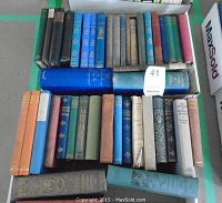 Top view of all the books showing the diversity in size and spine colors, including navy blue, green, red, orange and beige with gilded detailing and decoration on some spines.