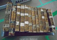 Box with 13 leather-bound volumes showing worn spines and manuscript labels