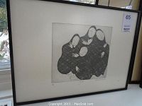 Full view of framed black and white abstract print of four faceless figures closely grouped, in black frame with white matte.