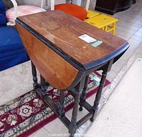 Closed view of the wooden occasional table showing rectangular shape with drop leaf sides folded down, turned legs and wear on tabletop.